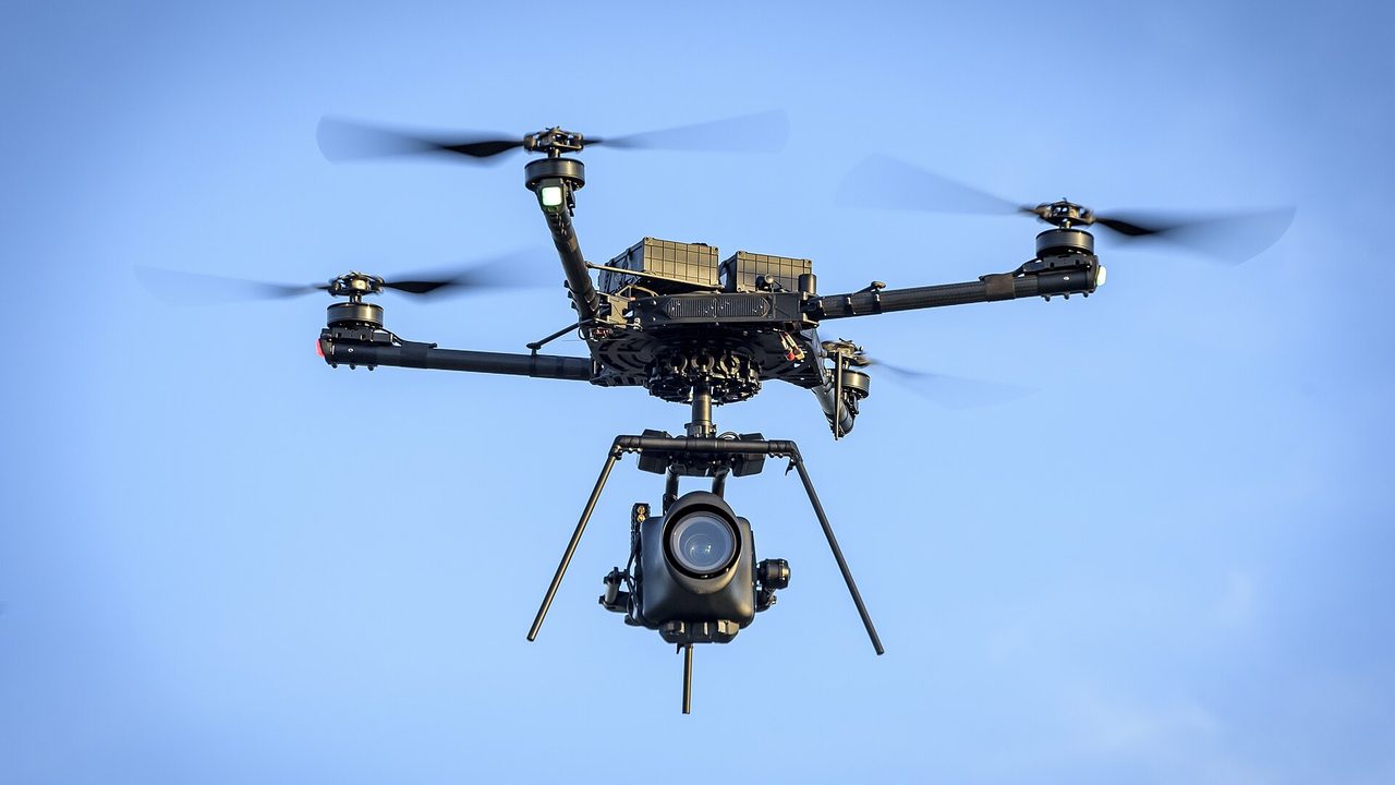 A black Alta-X uncrewed aircraft carrying a camera payload under its body, flying against a clear blue sky near Watsonville, California, on 18 November 2024.