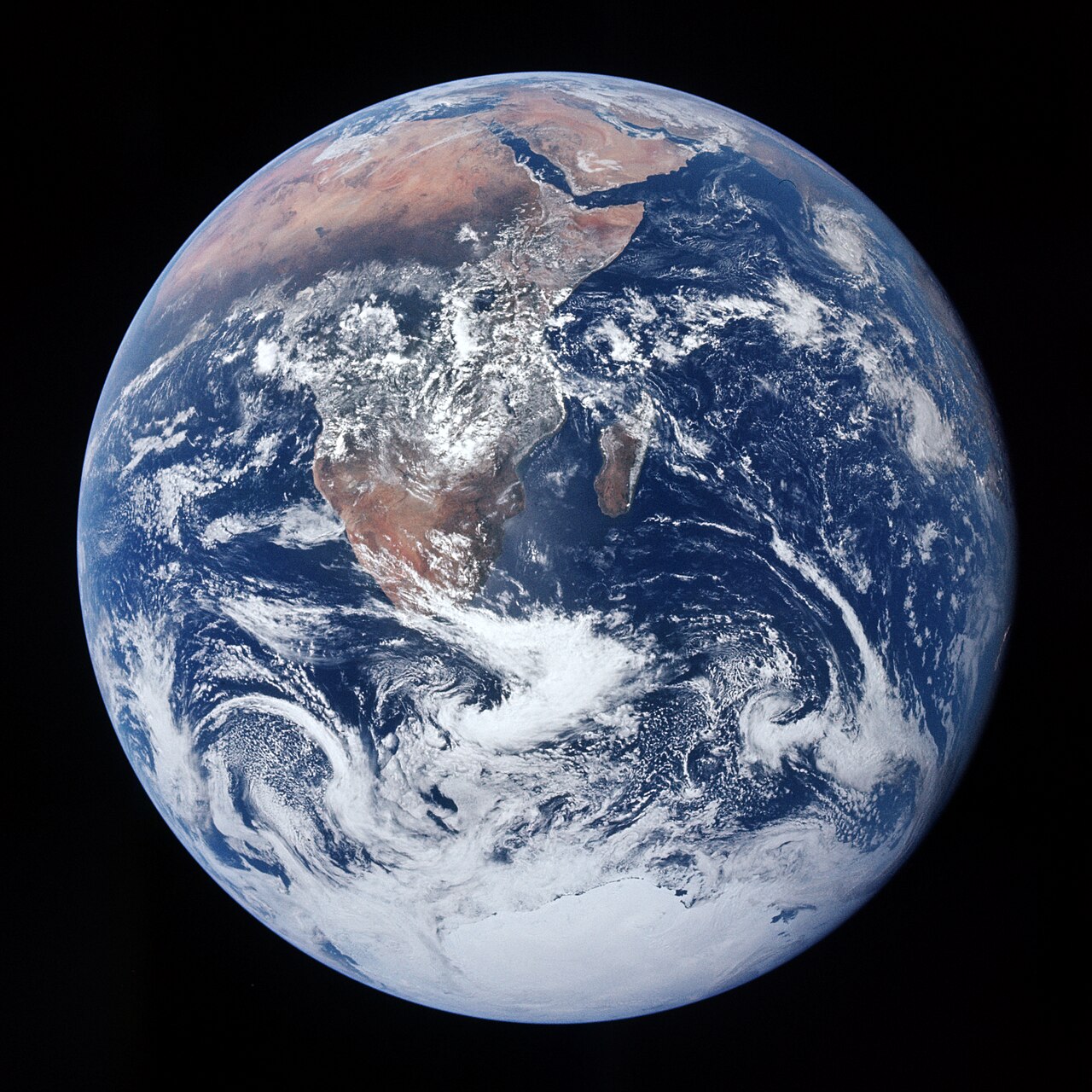 The Earth photographed from Apollo 17 on 7 December 1972: Africa fills the centre of the disc, with Madagascar to the south-east, the Arabian Peninsula at the top right and Antarctic ice at the bottom, under swirling white cloud.