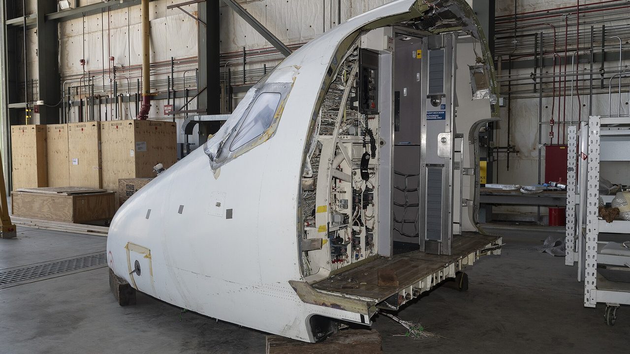 The cockpit section of a retired MD-90 airliner on the floor of a hangar at NASA's Armstrong Flight Research Center in California, March 2024, set aside to build a simulator for the X-66 research aircraft.